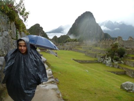 woman with poncho and umbrella at machu picchu