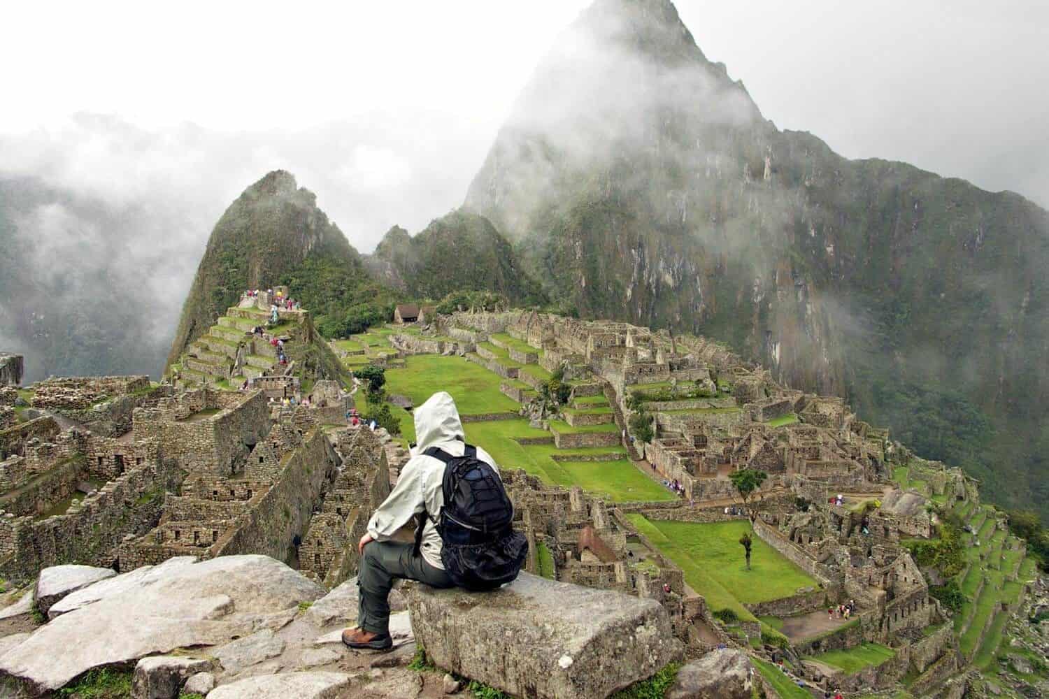 person from behind sitting in front of machu picchu