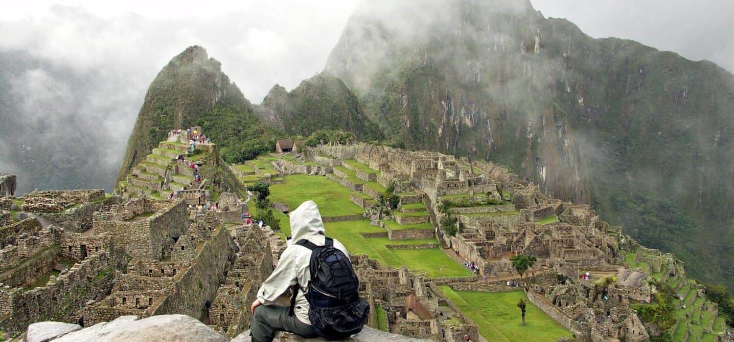 person from behind sitting in front of machu picchu