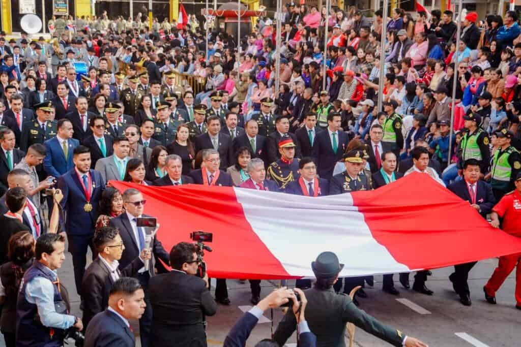 people during procession holding the Peruvian flag to celebrate Fiestas Patrias.