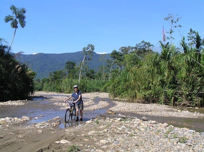 women with bycicle in river of peru jungle